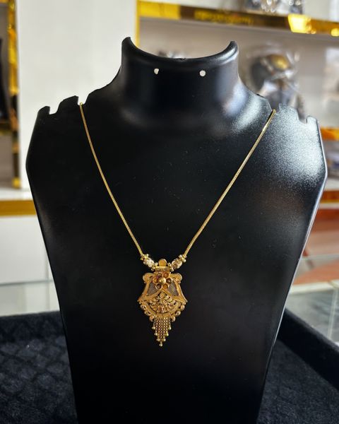 Gold kanthi with a small ornate pendant, on a display bust