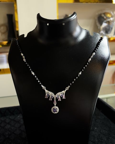 Mangalsutra with black beads and a wide pendant, on a display bust