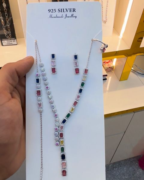 Silver necklace set with coloured stones and matching earrings, on its display card